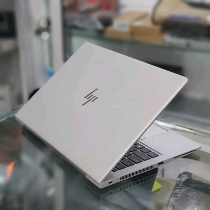 HP EliteBook open on desk with stylus pen showing Shopinverse wallpaper