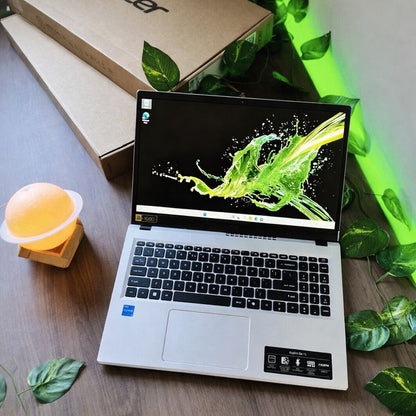Acer Aspire Go 15 open on wooden table with Acer box and green plants in background