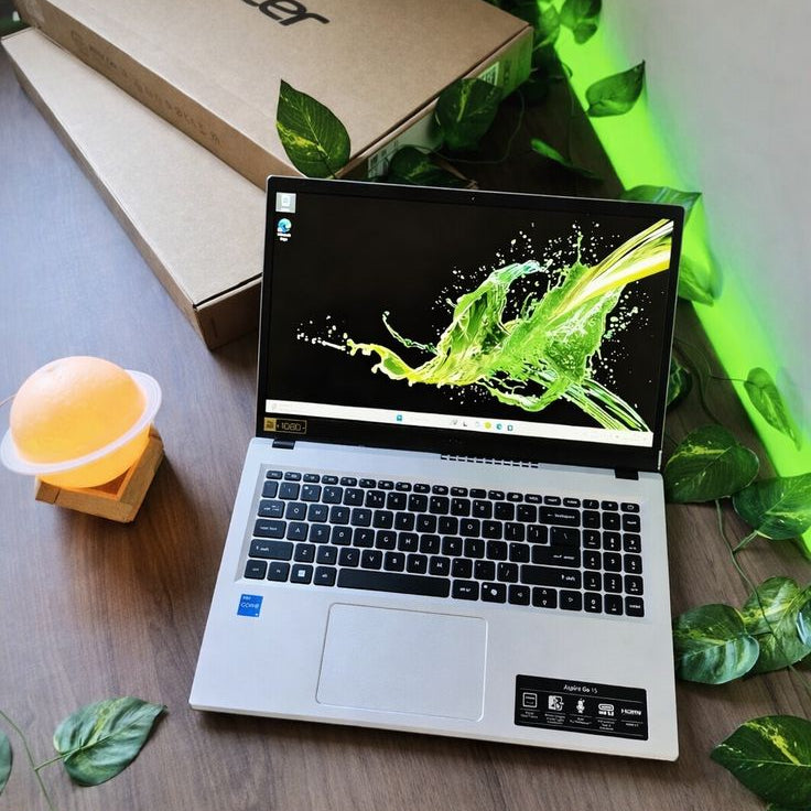 Acer Aspire Go 15 open on wooden table with Acer box and green plants in background
