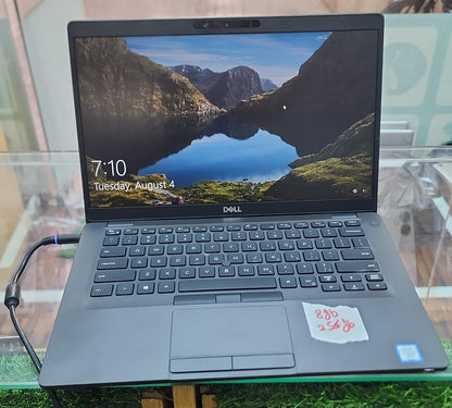 Dell Latitude open on glass surface showing Windows 10 lock screen with 8GB 256GB label on trackpad