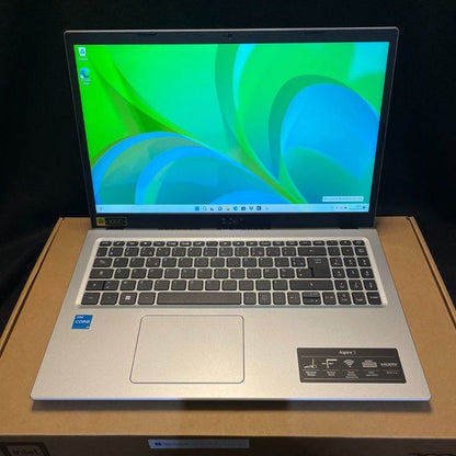 Acer Aspire 3 open on box showing Windows 11 green wallpaper with Intel Core i5 badge and Aspire 3 sticker